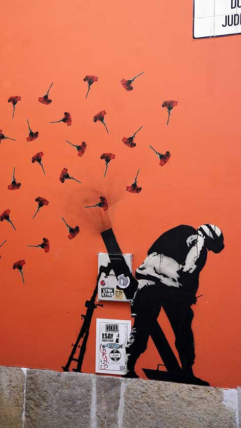 A mural attributed to the Portuguese Banksy Adres showing carnations fired from a mortar in Lisbon.